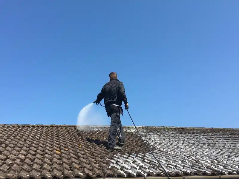 Elle s'est couverture en train d'appliquer un traitement par pulvérisation sur une toiture salle à Avon en Seine-et-Marne